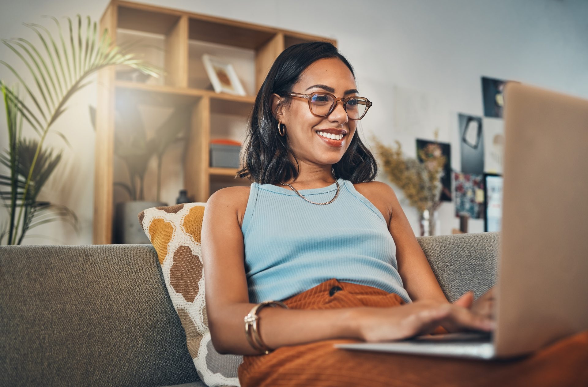 Female student sat on sofa working on laptop