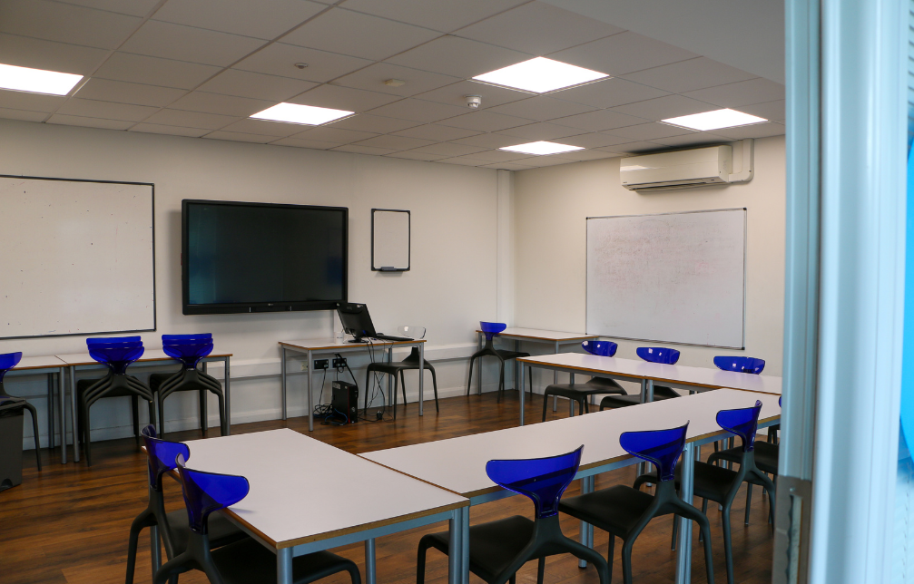 Empty class room with tables and chairs and a large screen